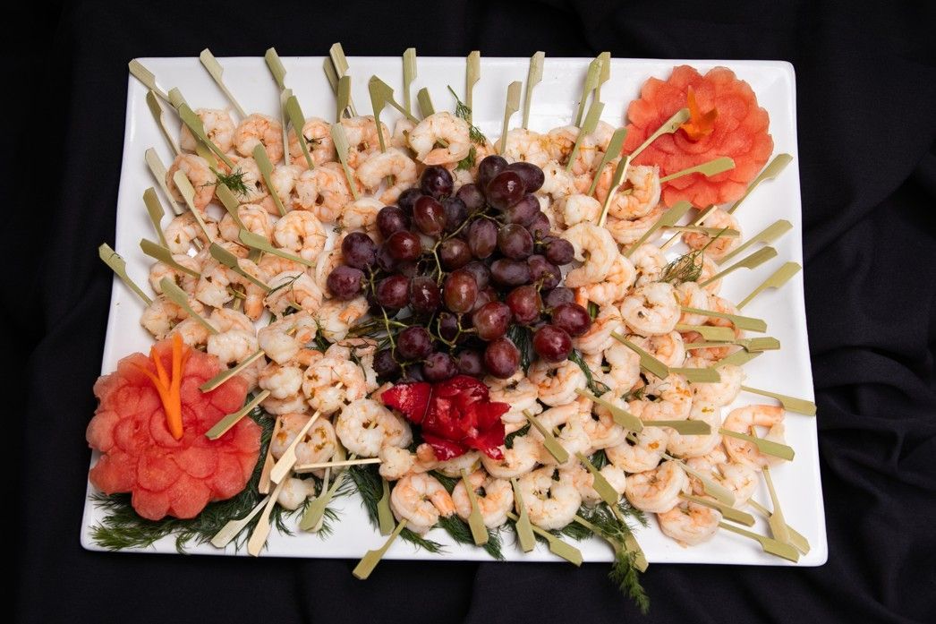 A white plate topped with shrimp , grapes and watermelon.