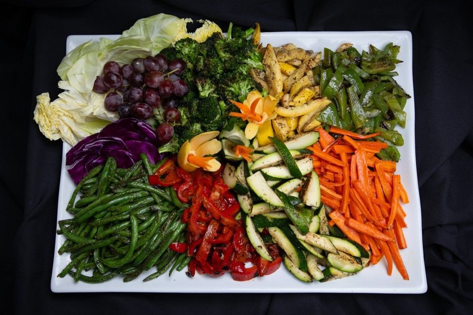 A white plate topped with a variety of vegetables and fruit.