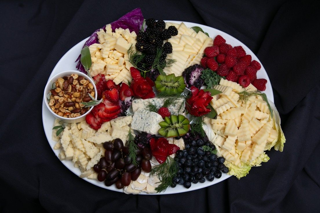 A white plate topped with a variety of fruits and cheeses.