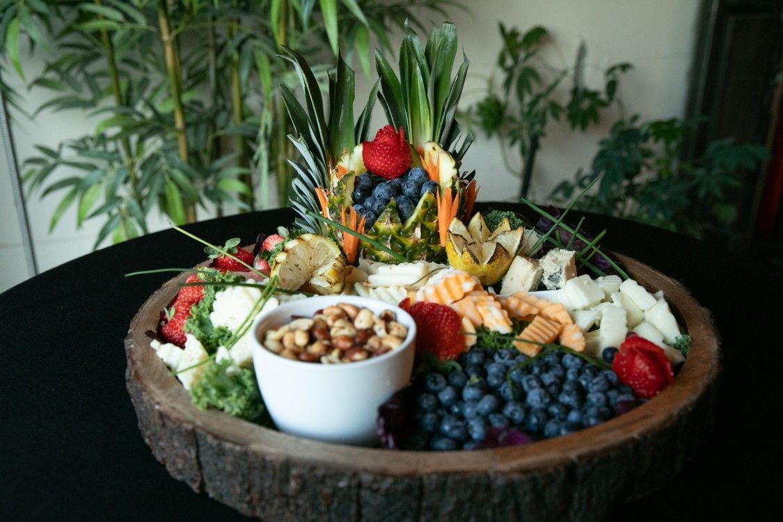 A wooden tray filled with fruits and nuts on a table.