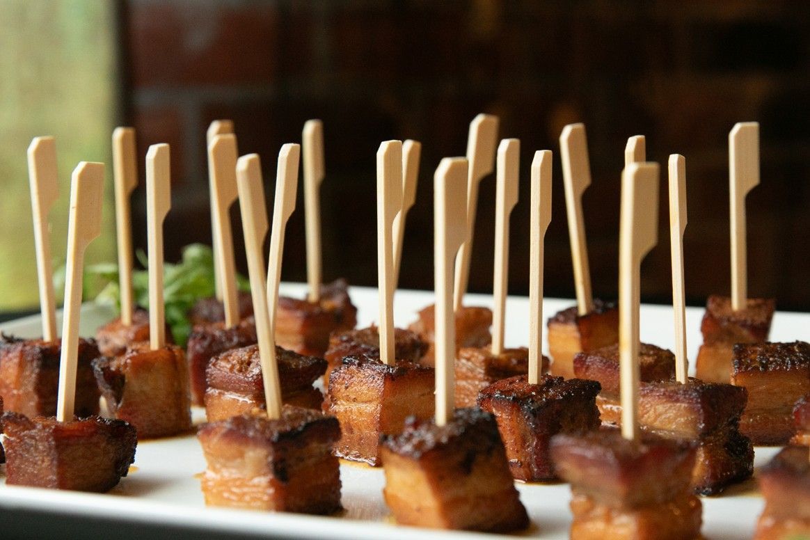 A white plate topped with small pieces of meat on toothpicks.