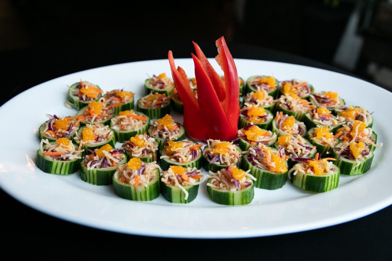 A white plate topped with sliced cucumbers and a red pepper.