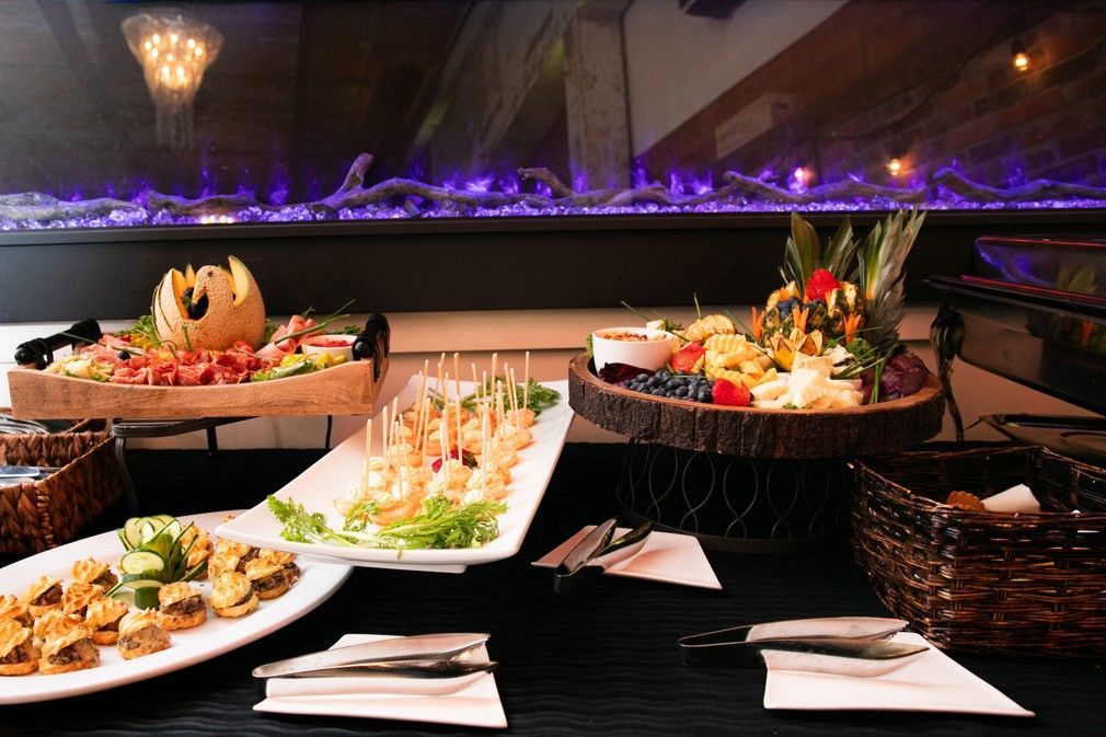 A buffet table with plates of food and a fireplace in the background.