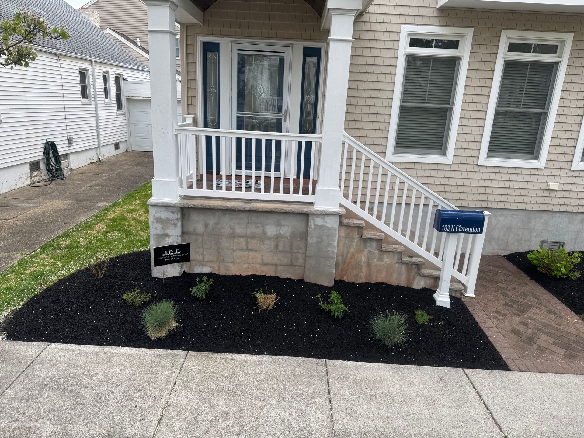 House exterior with front porch and small landscaping bed filled with black mulch.