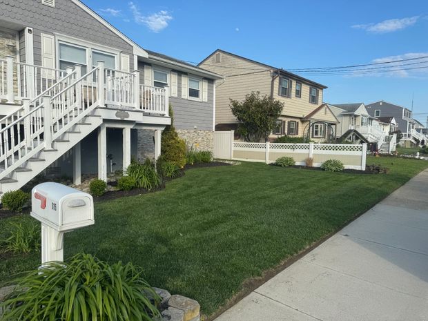 Row of houses with green lawns, mailbox in foreground, clear blue sky.
