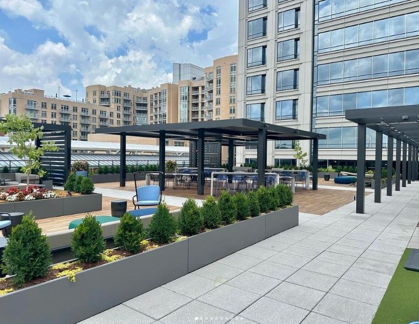 Modern apartment courtyard with pergolas, landscaped planters, and tall buildings in the background