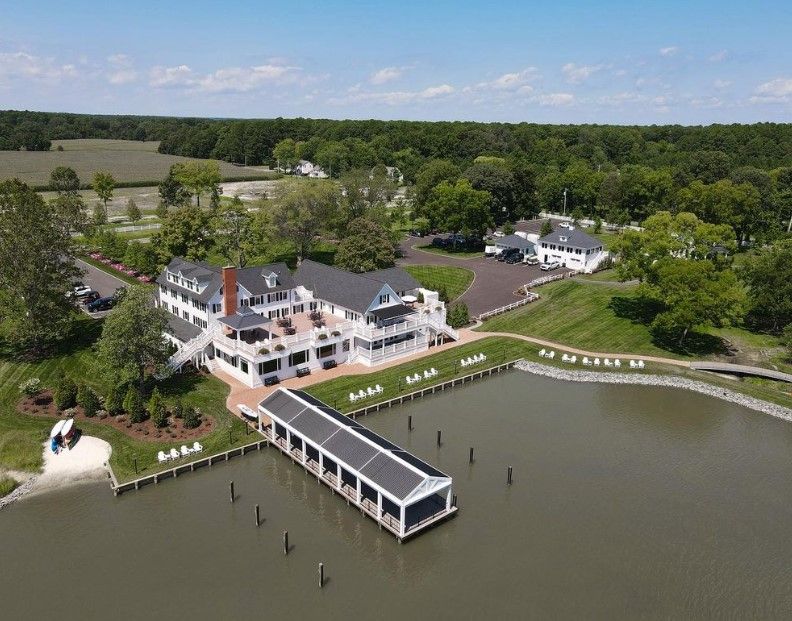 Aerial view of a waterfront inn with docks, boats, and a small bay surrounded by trees