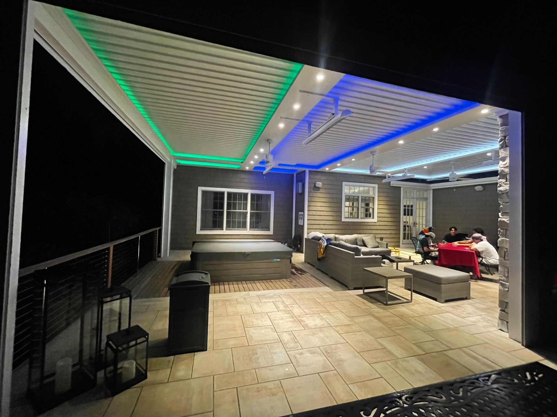 Covered patio with LED-lit ceiling, outdoor seating, and dining area at night.