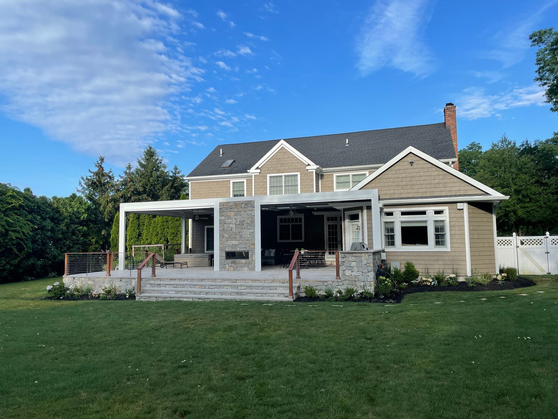 Suburban house with gray siding, white trim, and a large front lawn under a blue sky