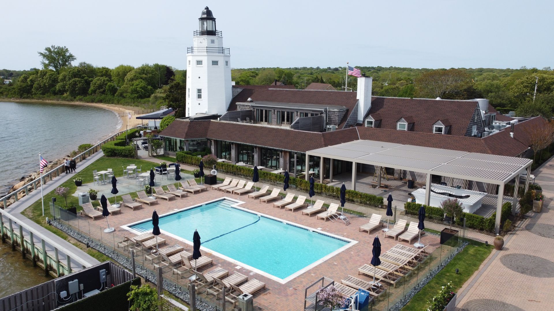 Lighthouse resort with outdoor pool, deck chairs, and waterfront view on a sunny day