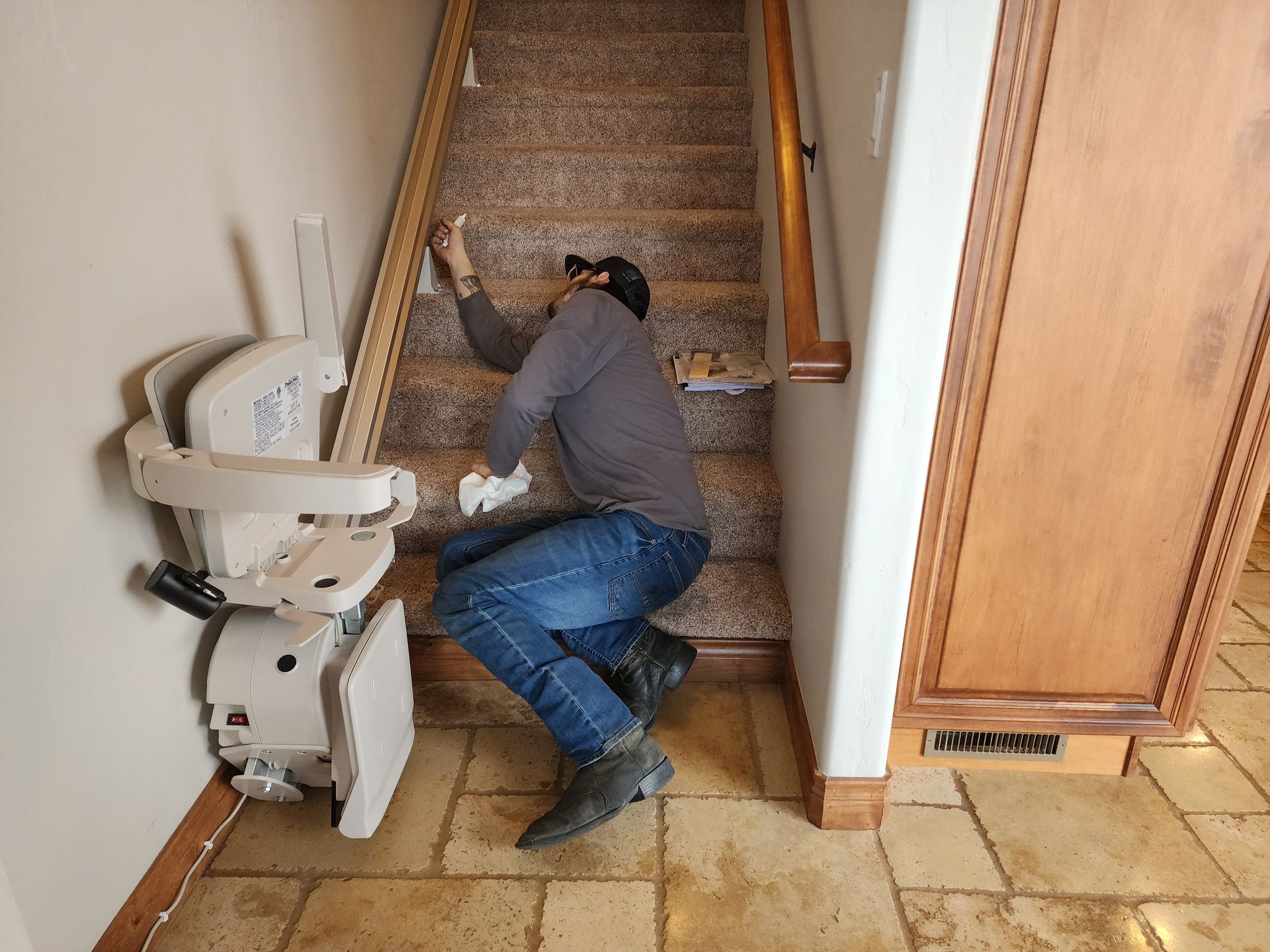 a man is kneeling on the floor next to a stair lift.