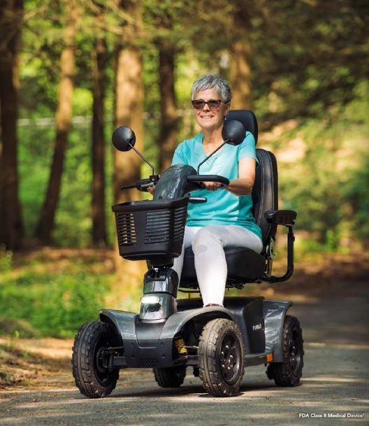 A woman is sitting on a mobility scooter on a road.