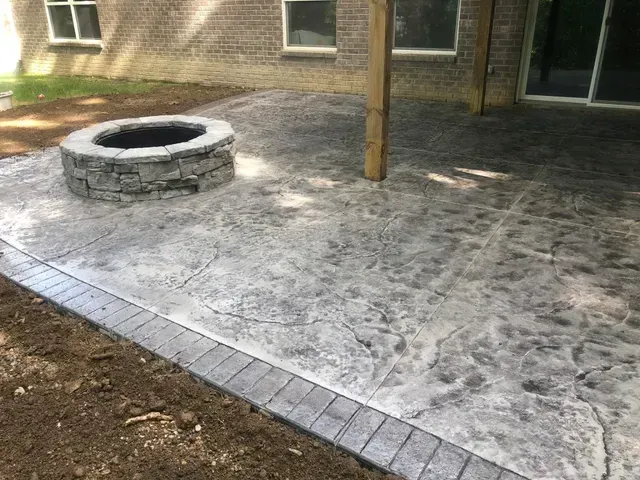 A concrete patio with a fire pit in the middle of it.