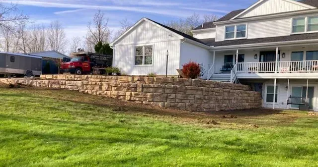 A large white house with a stone wall in front of it.