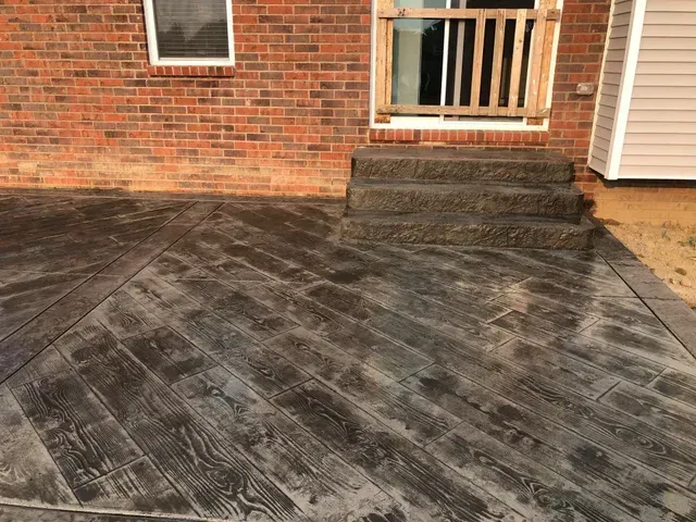 A brick house with a concrete driveway and stairs in front of it.
