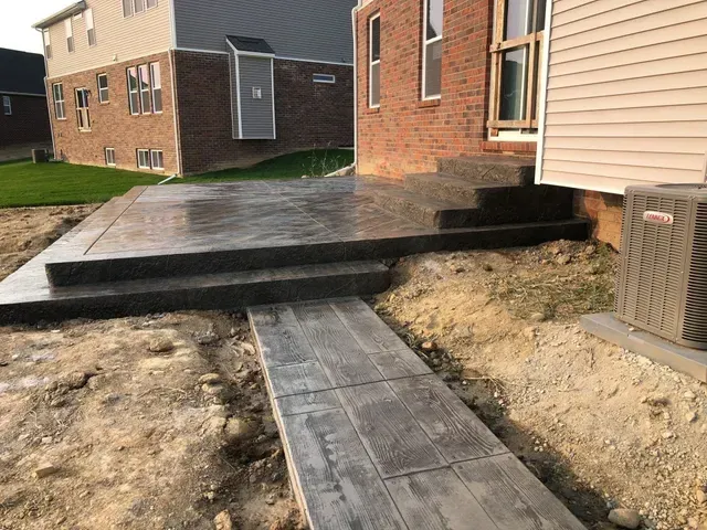 A brick house with a concrete walkway leading to it.