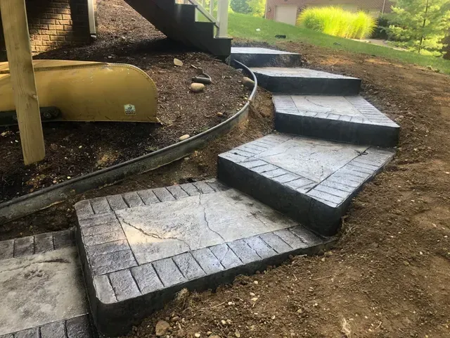 A set of concrete steps leading up to a deck in a yard.