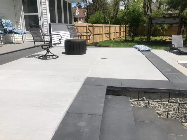 A patio with chairs and a fire pit in the backyard of a house.