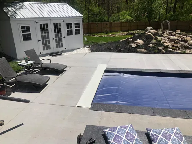 A pool with a blue cover and a shed in the background