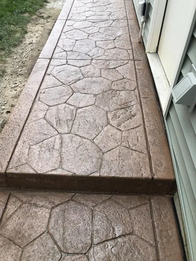 A concrete walkway with steps leading to a house.