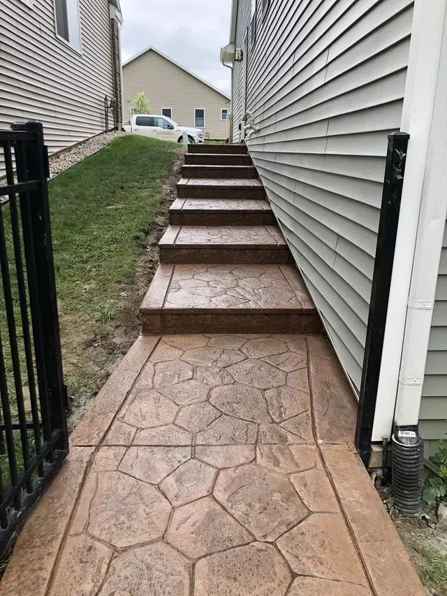 A concrete walkway with stairs leading up to a house.