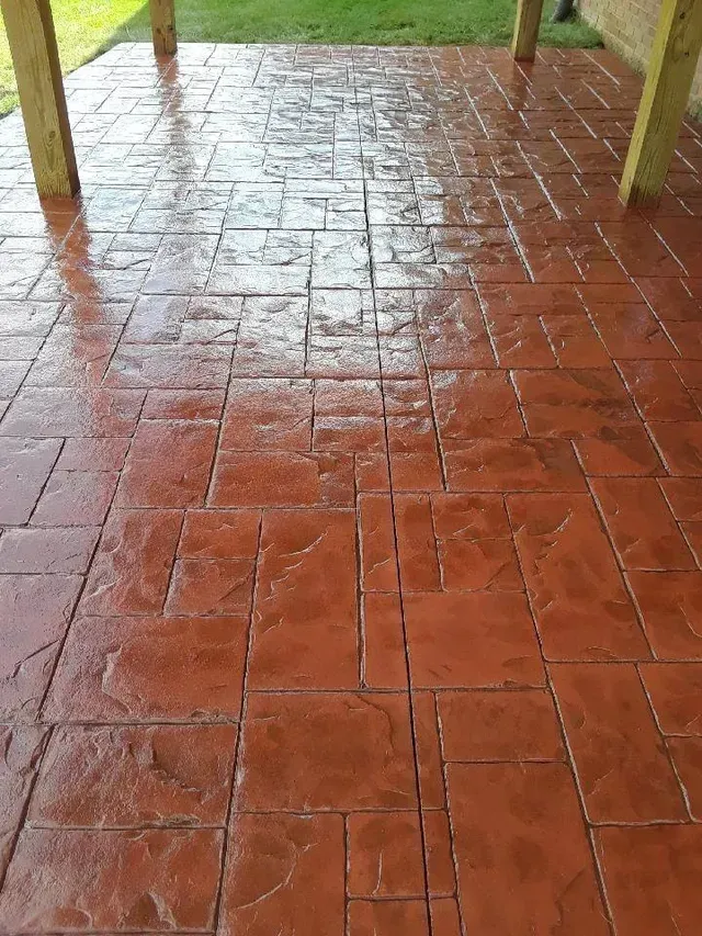 A patio with a red tile floor and wooden pillars.