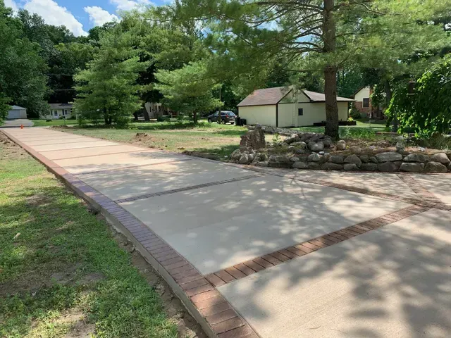 A concrete driveway with a brick border and a shed in the background.