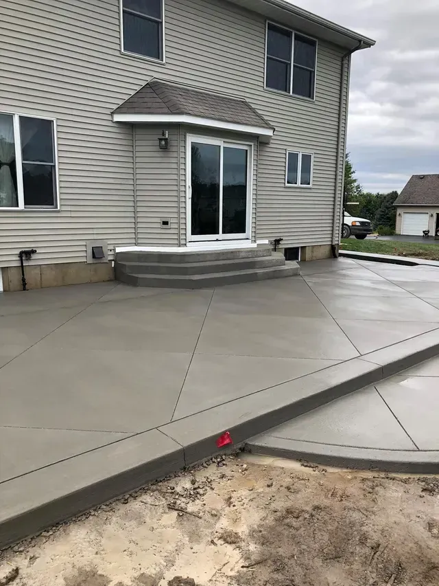 A large house with a concrete patio in front of it.