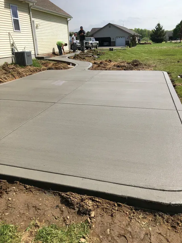 A concrete driveway is being built in front of a house.