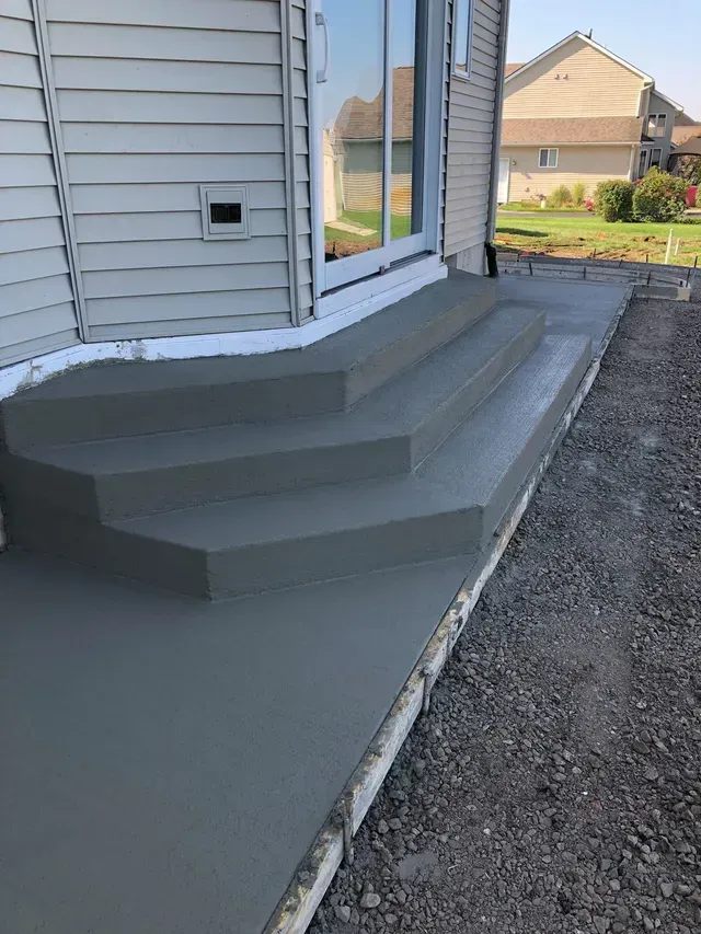A concrete porch with stairs leading up to a house.