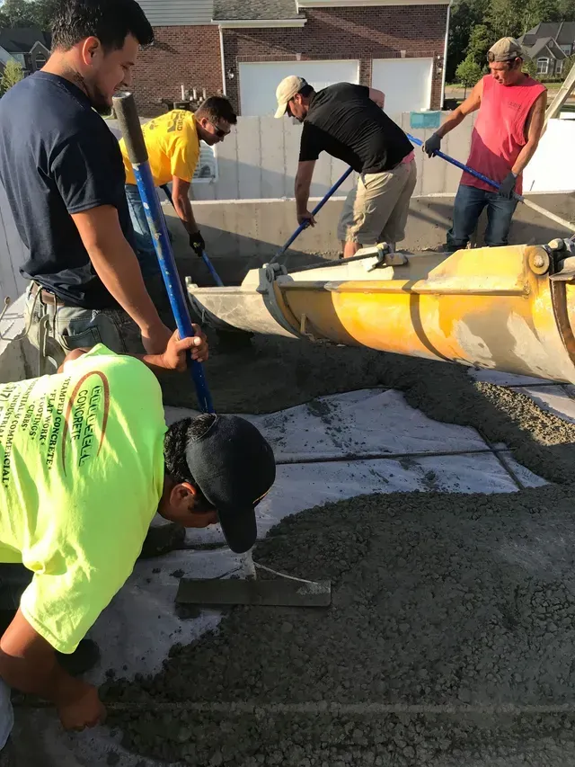 A group of men are working on a concrete driveway.