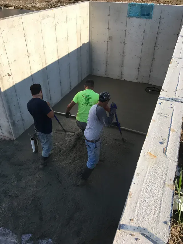 A group of construction workers are working on a concrete floor.