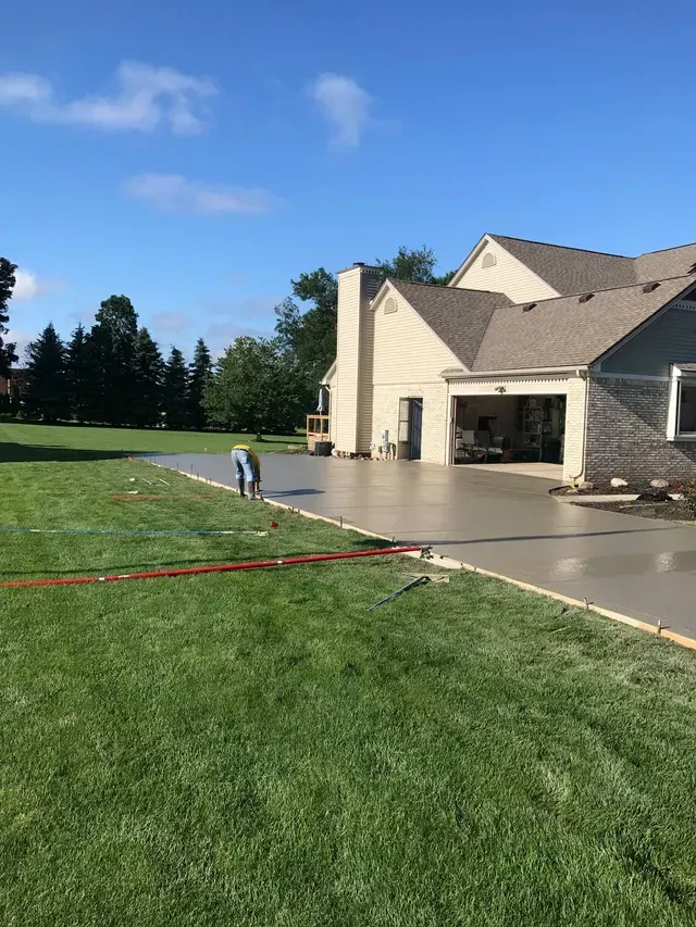 A concrete driveway is being installed in front of a house.