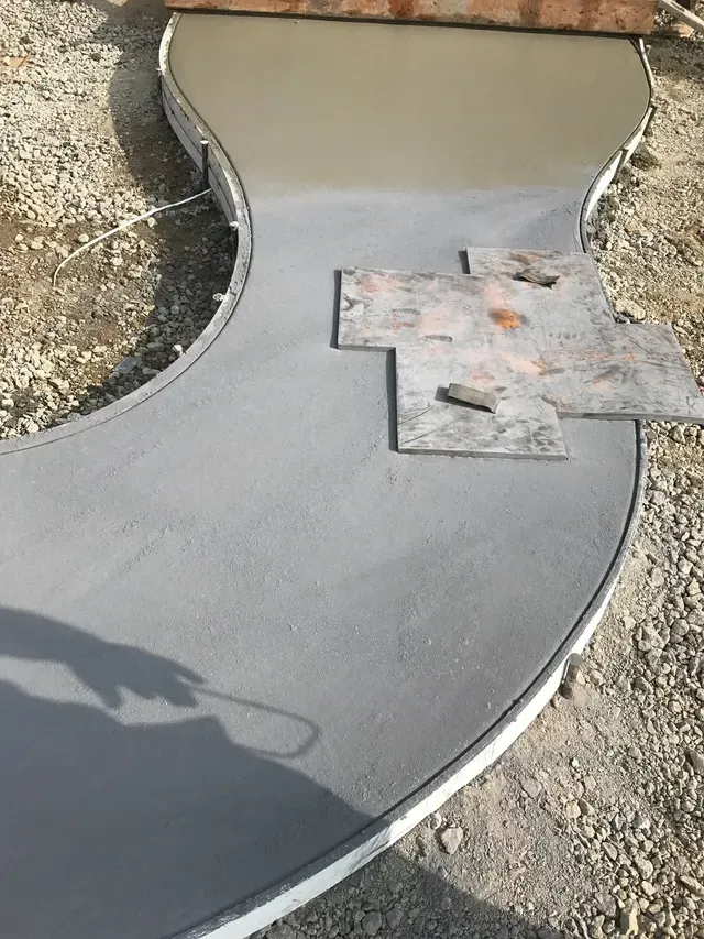 A concrete walkway is being built on a gravel road.