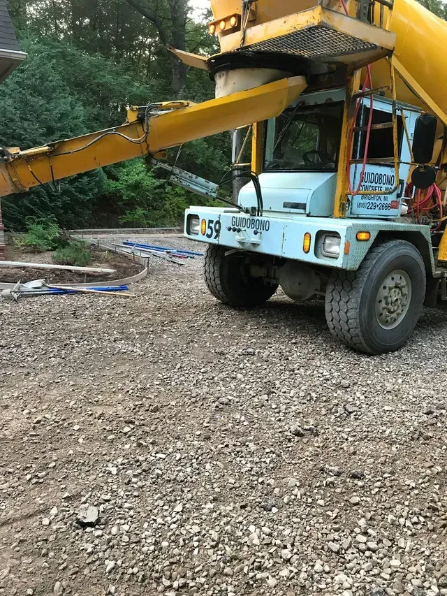 A concrete mixer truck is sitting on a gravel road.