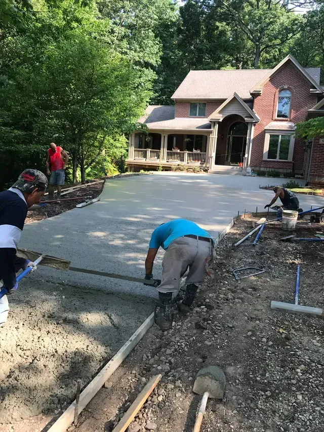 A group of men are working on a driveway in front of a house.
