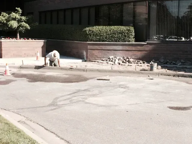 A man is working on the sidewalk in front of a building
