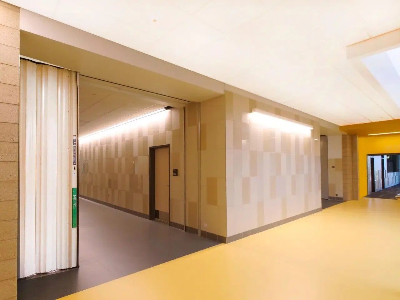 A long hallway with a yellow floor and a sliding door
