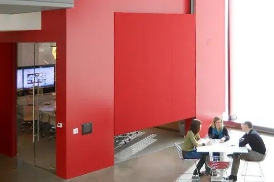 A group of people are sitting around a table in front of a red wall
