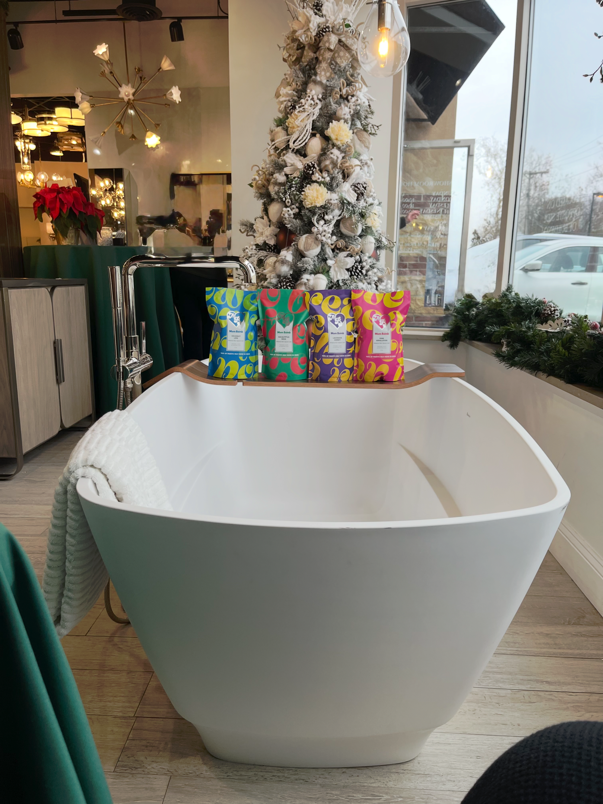 White bathtub display with wrapped gifts, Christmas tree in the background.