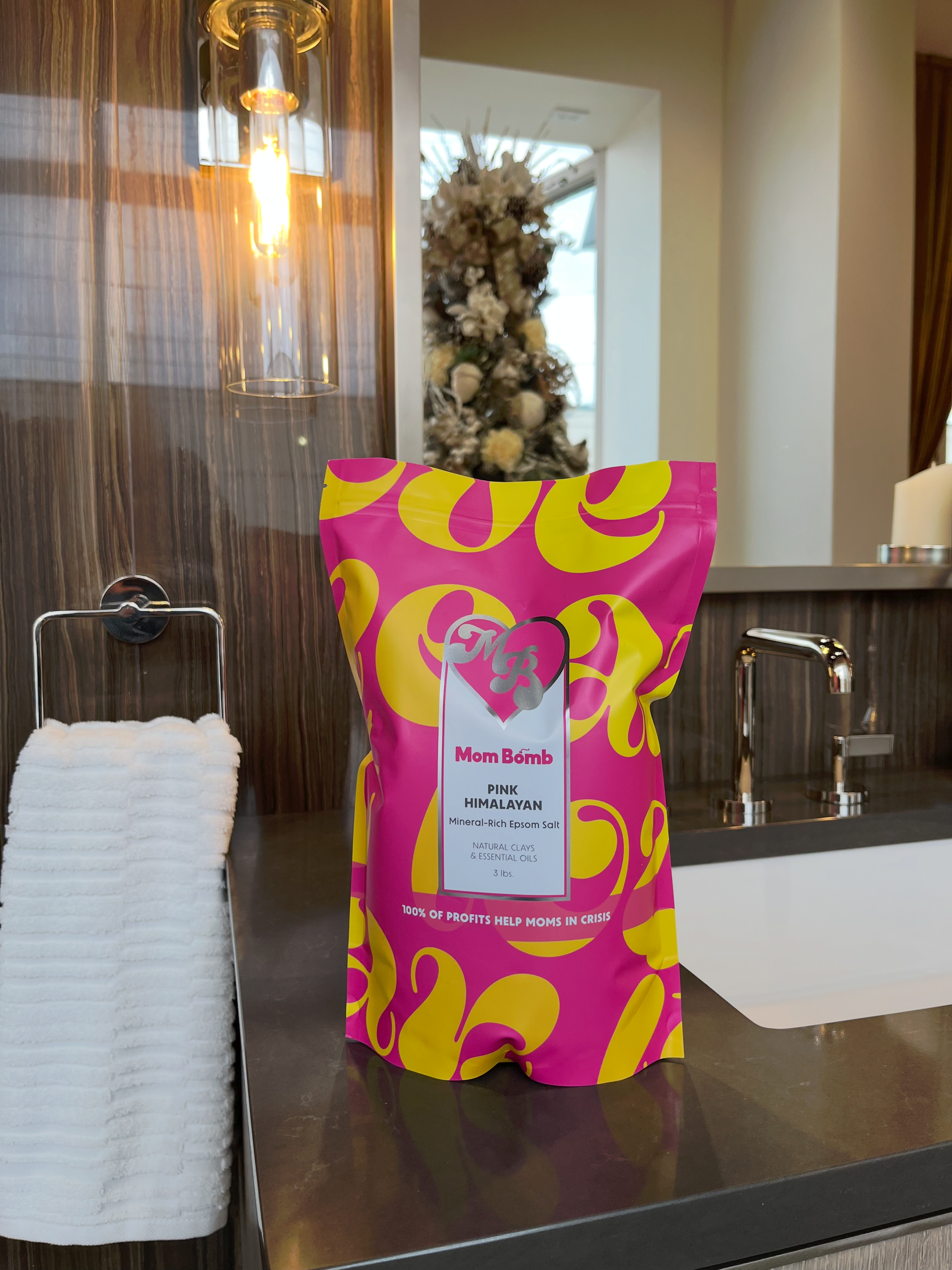 Pink and yellow bag of product on a countertop with a towel rack and sink in background.