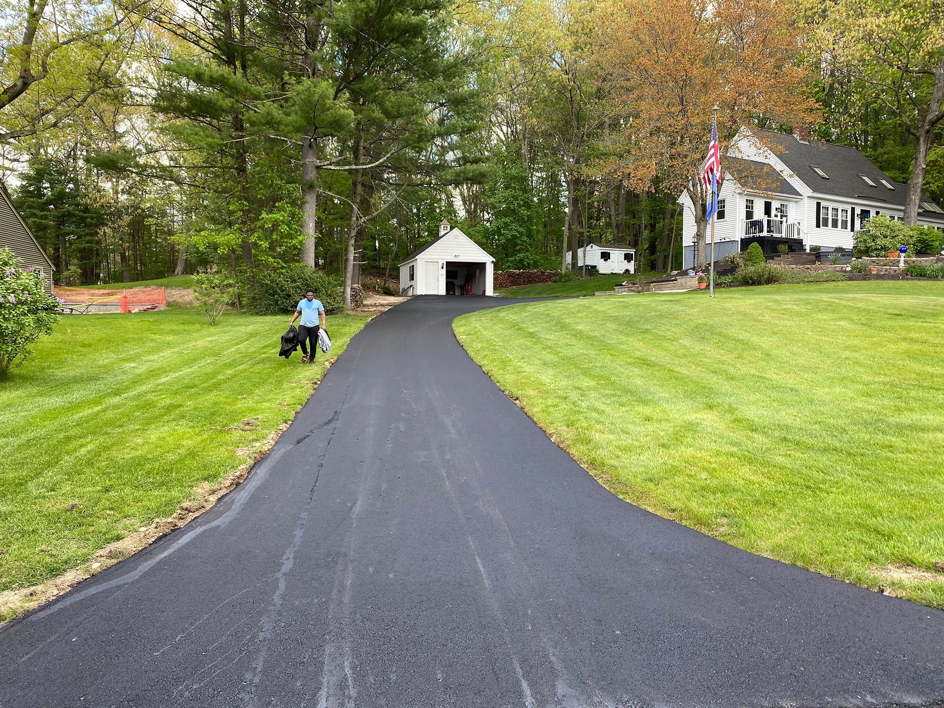 A man is walking down a driveway next to a house.