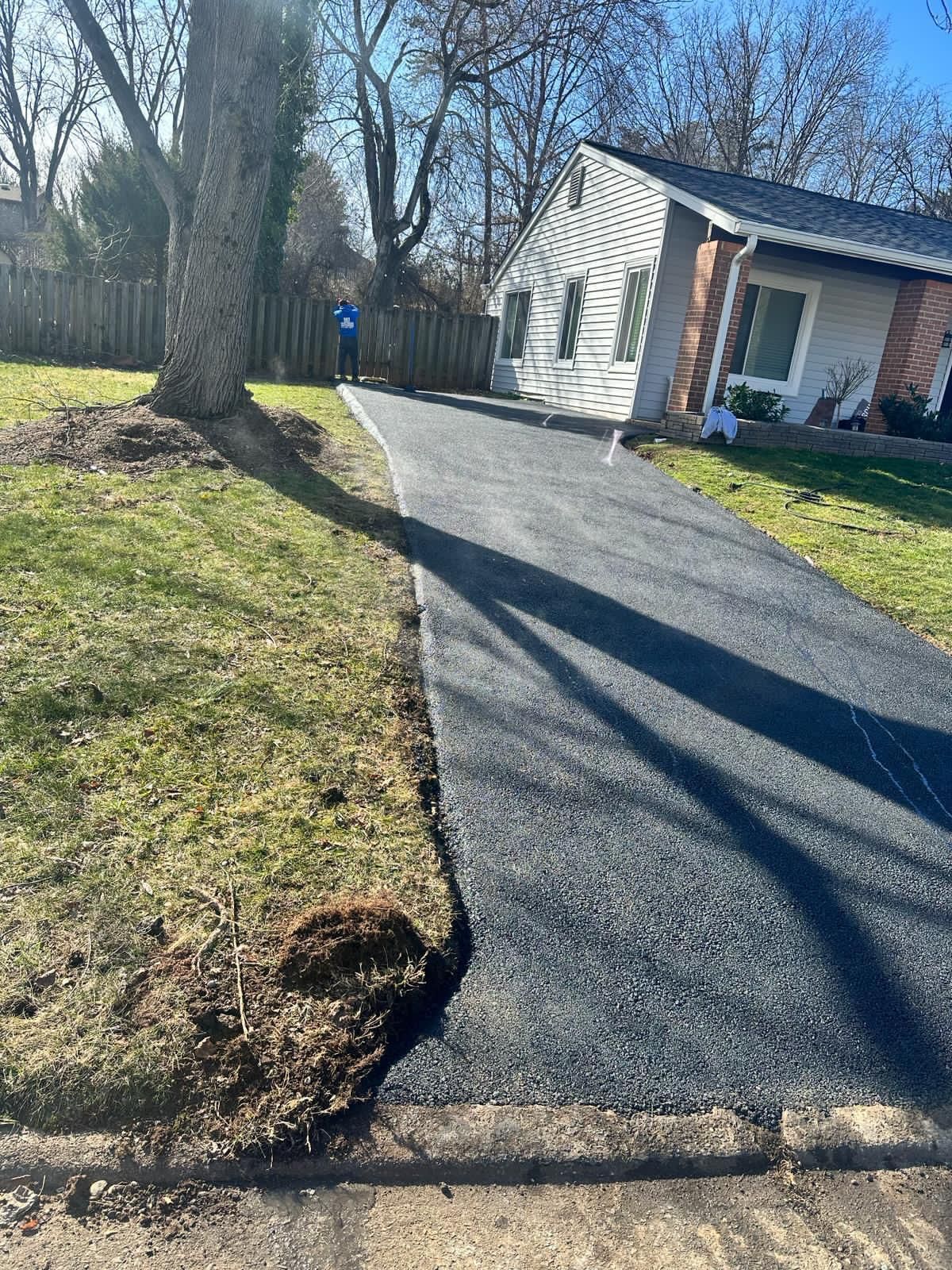 A driveway leading to a house with a mailbox on the side of it.