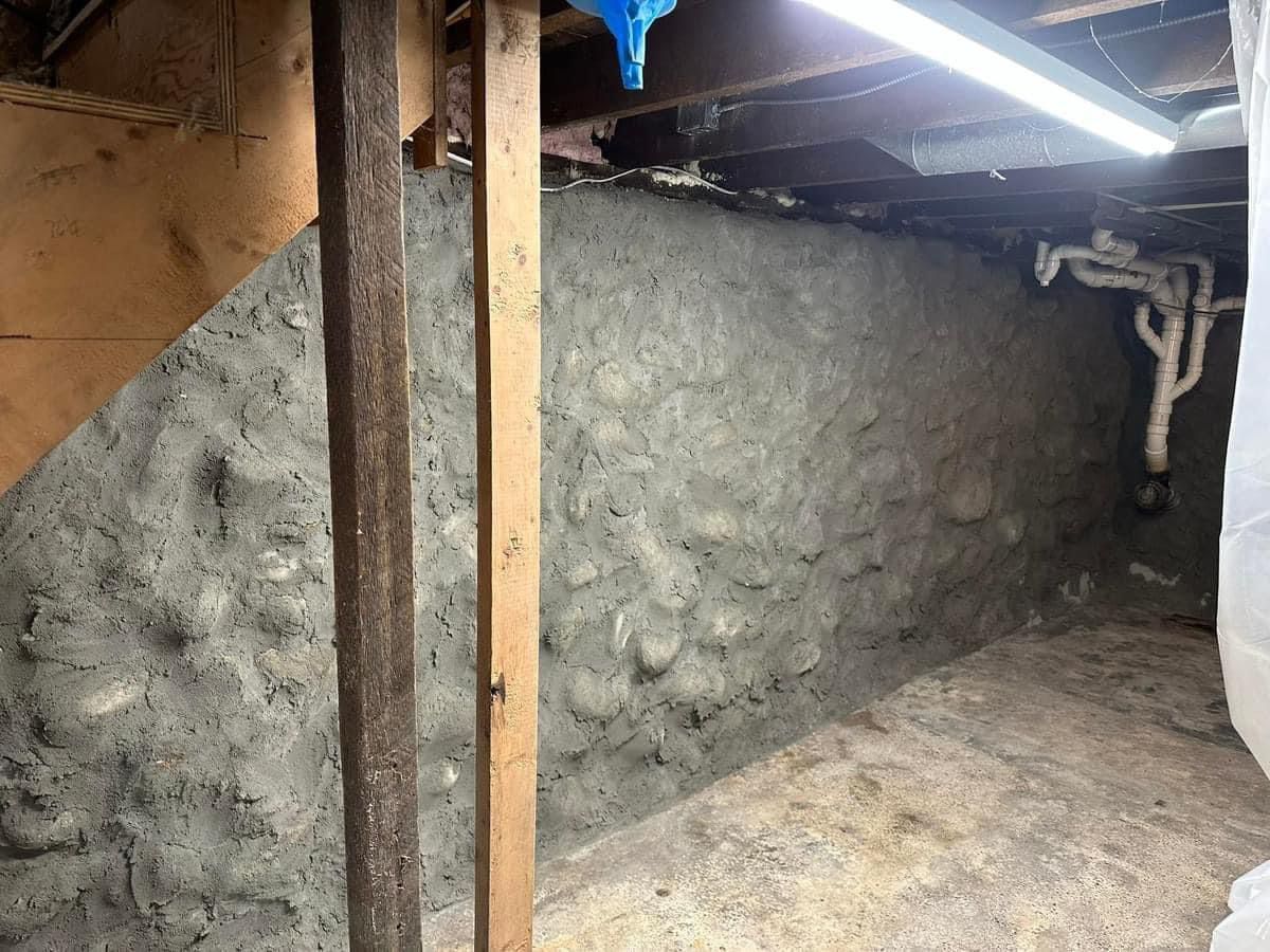 A basement with a concrete wall and wooden beams.