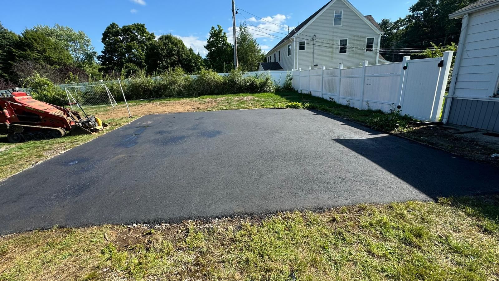 A tractor is parked on the side of a driveway next to a house.