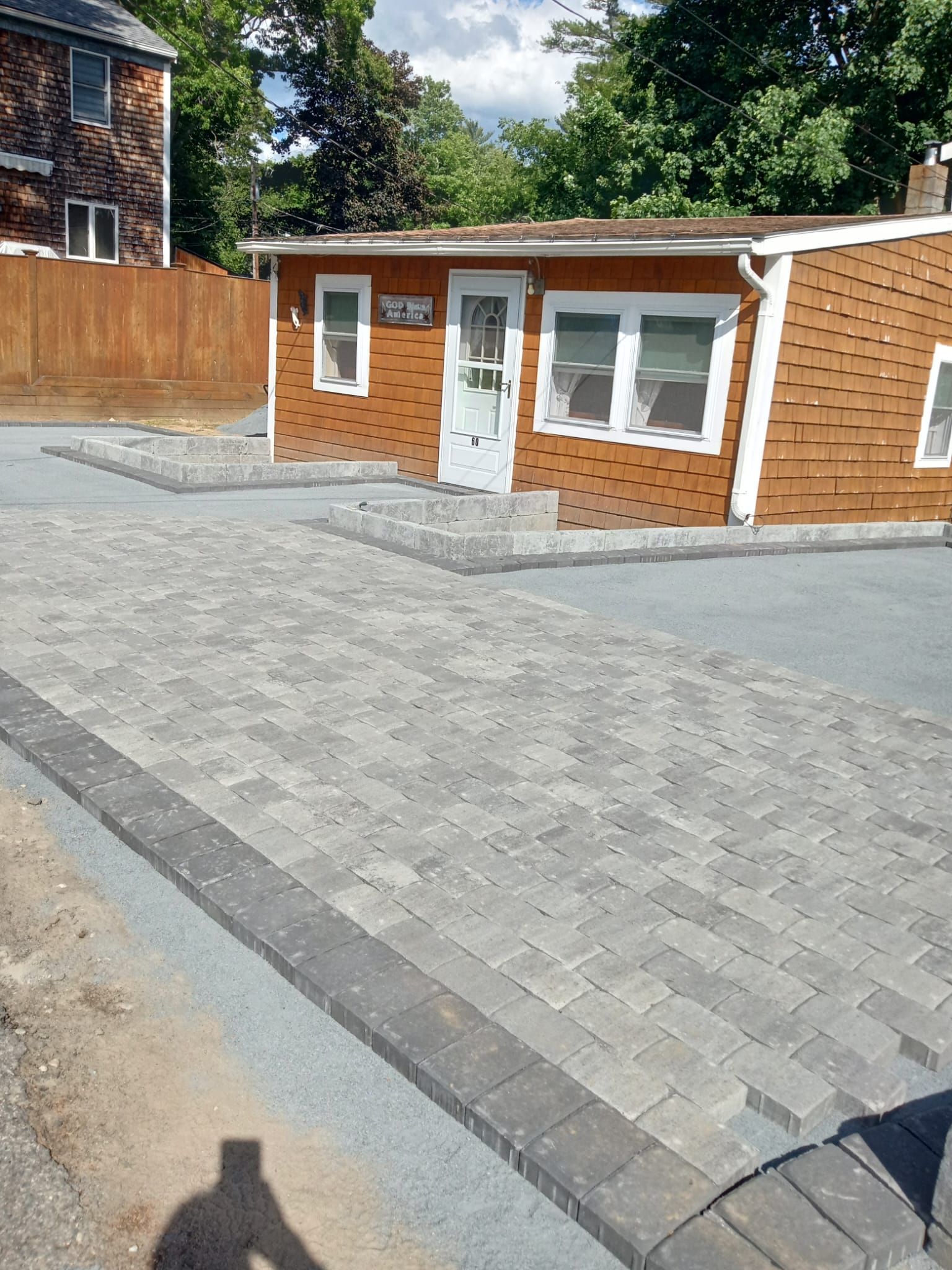 A small house with a brick driveway in front of it