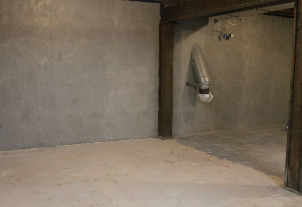 An empty room with a concrete floor and a concrete wall.