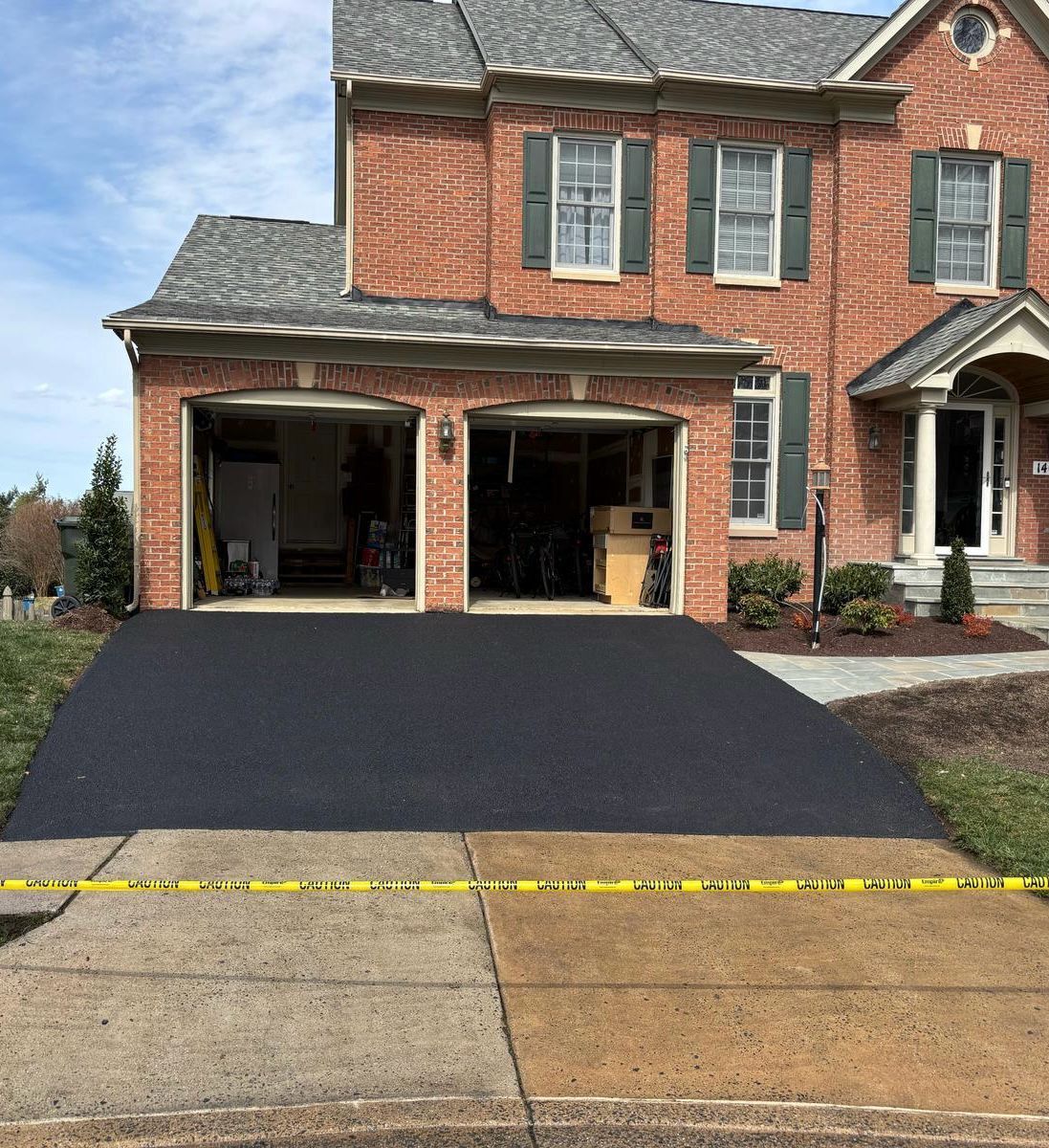 A brick house with a black driveway in front of it