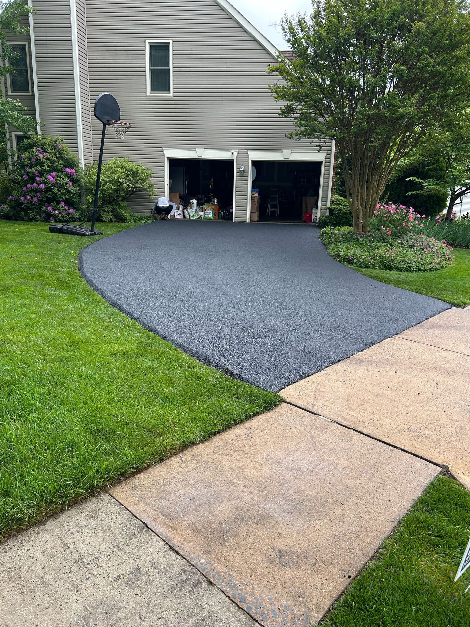 A driveway leading to a house with a garage and a sidewalk.