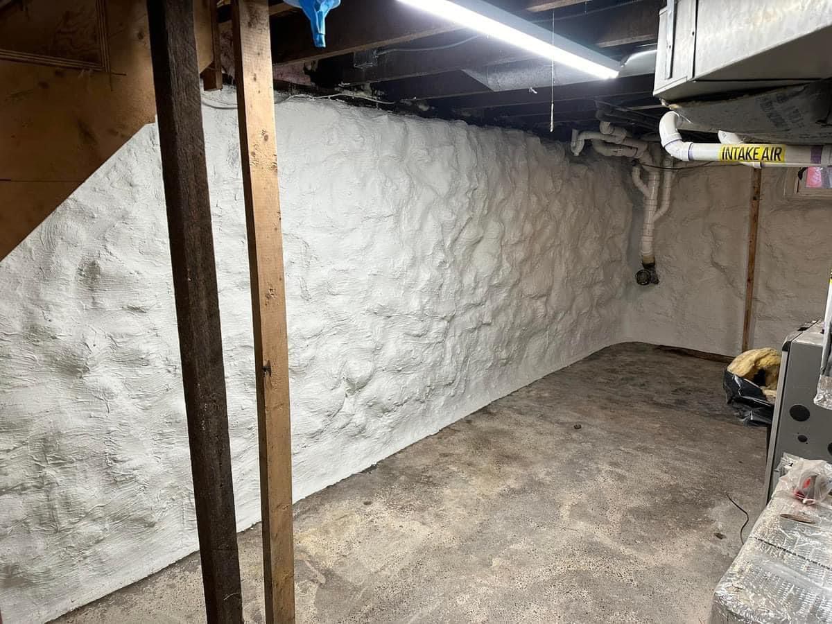 A basement with a white wall and wooden beams.